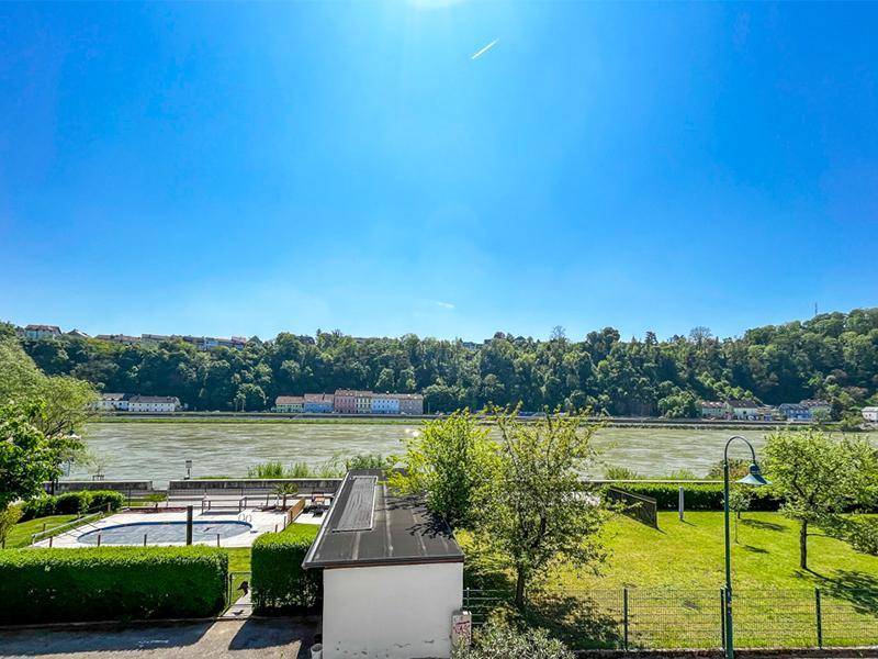 Weitläufiger Blick auf den Fluss, die bewaldeten Hügel und die gegenüberliegende Uferbebauung.