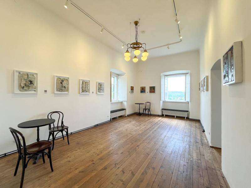 Heller Galerieraum mit Holzdielenboden, weißen Wänden und Kunstwerken, ideal für Ausstellungen.