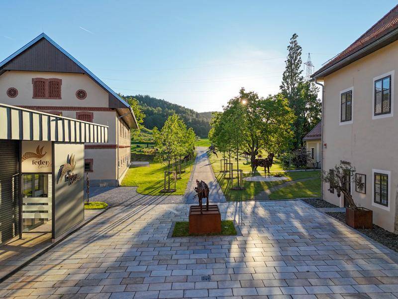 Innenhof bei Sonnenuntergang mit gepflastertem Bereich, Bäumen und Gebäuden in warmem Licht.
