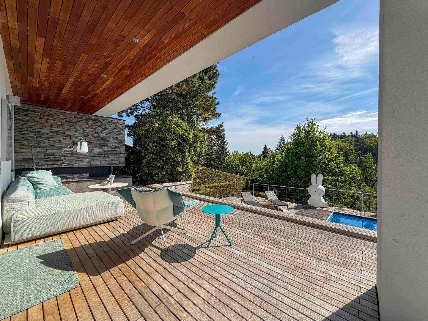 Überdachte Holzterrasse mit bequemen Loungemöbeln und weitem Blick in die Natur.