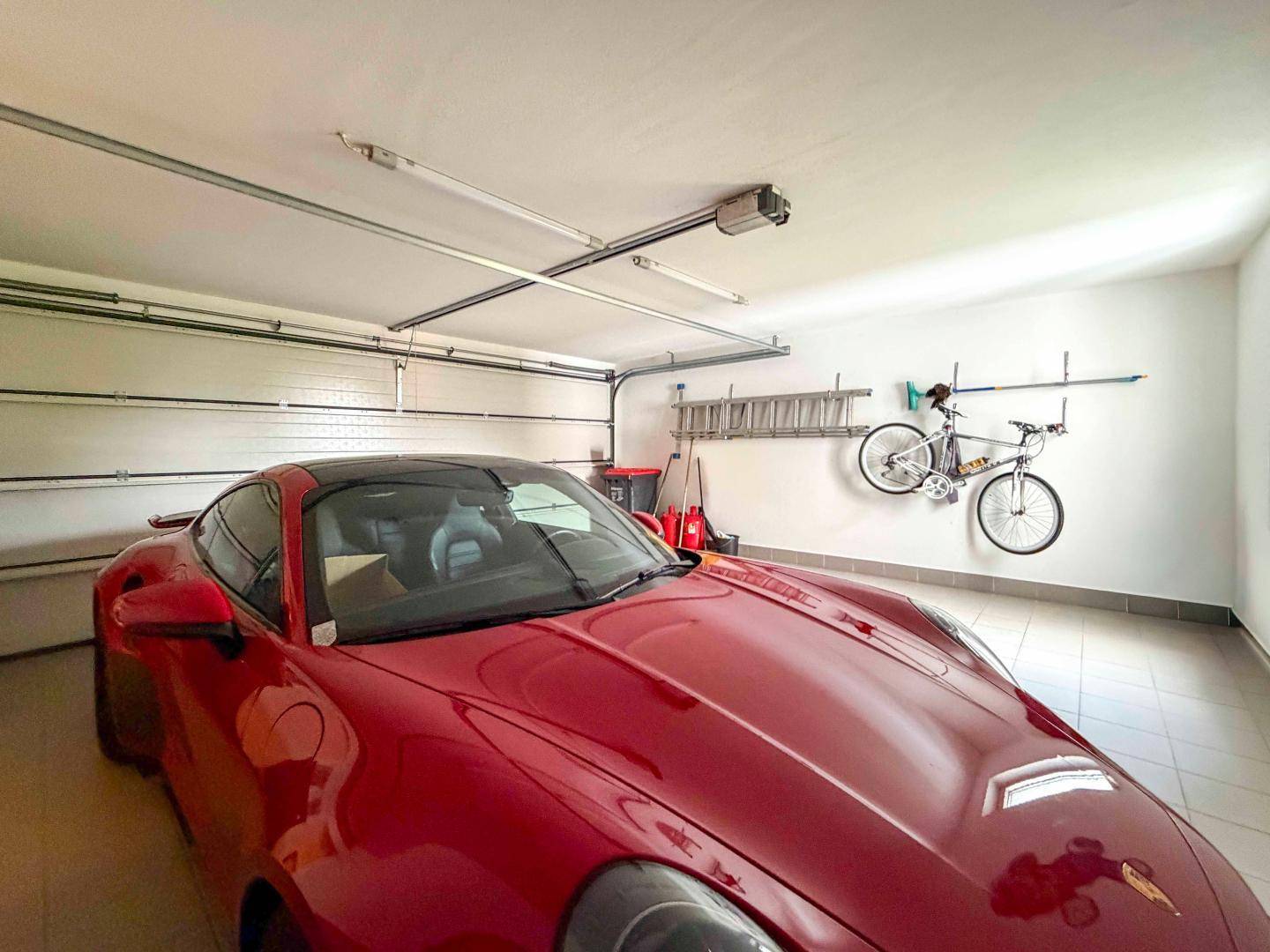 Geräumige Garage mit einem Sportwagen, Fahrradaufhängung und ausreichend Stauraum.