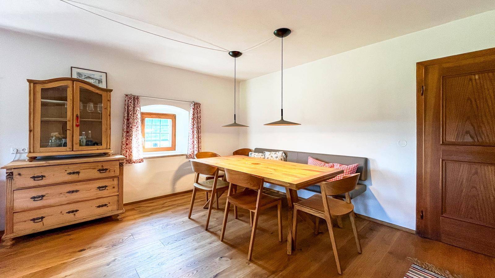 Gemütlicher Essbereich mit Holztisch, Sitzbank und traditionellem Holzschrank, ideal für Familienmahlzeiten.