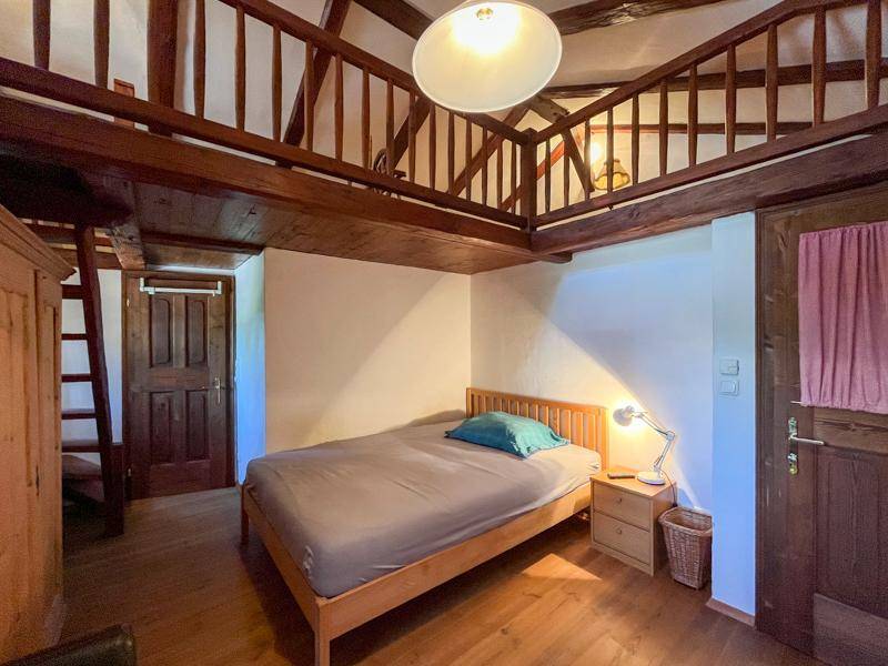 Gemütliches Schlafzimmer mit Holzboden, Doppelbett und Zugang zu einer oberen Galerie.