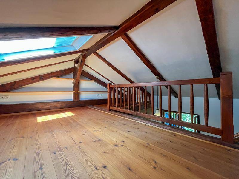 Helle Galerie im Dachgeschoss mit Holzboden, sichtbaren Balken und Dachfenster.