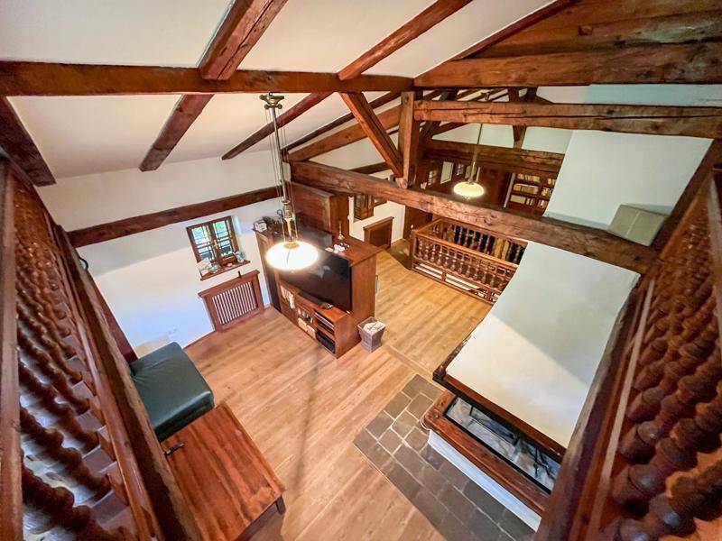 Blick von der Galerie auf das geräumige Wohnzimmer mit Kamin und Holzbalken.