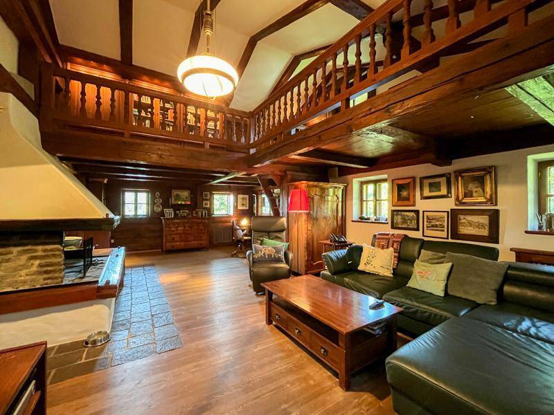 Großzügiges Wohnzimmer mit Galerie, Kamin und sichtbaren Holzbalken, traditionell eingerichtet.