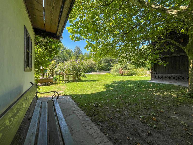 Ruhiger Gartenbereich mit einer Holzbank und Blick auf die grüne Landschaft.