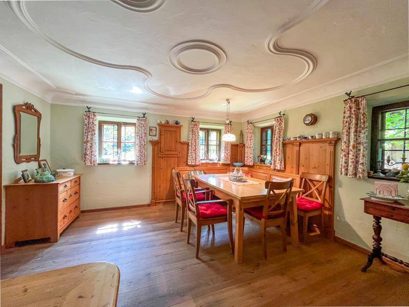 Gemütliches Esszimmer mit Holzboden, traditionellen Holzmöbeln und dekorativer Stuckdecke.
