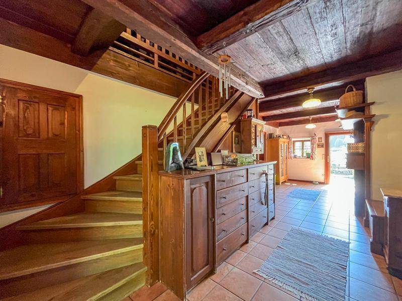 Traditioneller Eingangsbereich mit Holztreppe, Holzbalken und Terrakotta-Fliesenboden.