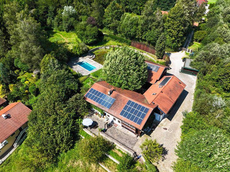 Luftaufnahme des Anwesens mit Haupthaus, Nebengebäuden, Pool und Photovoltaikanlagen.