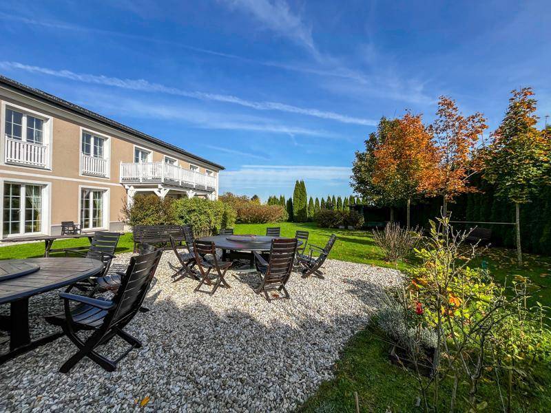 Großer Garten mit mehreren Sitzgelegenheiten und Blick auf das elegante Landhaus.