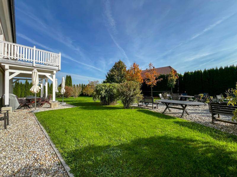 Weitläufiger Garten mit Rasenflächen, Kieswegen und verschiedenen Sitzbereichen im Freien.