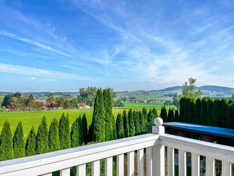 Panoramablick von einem Balkon über die weite, grüne Landschaft mit Bäumen und Häusern.