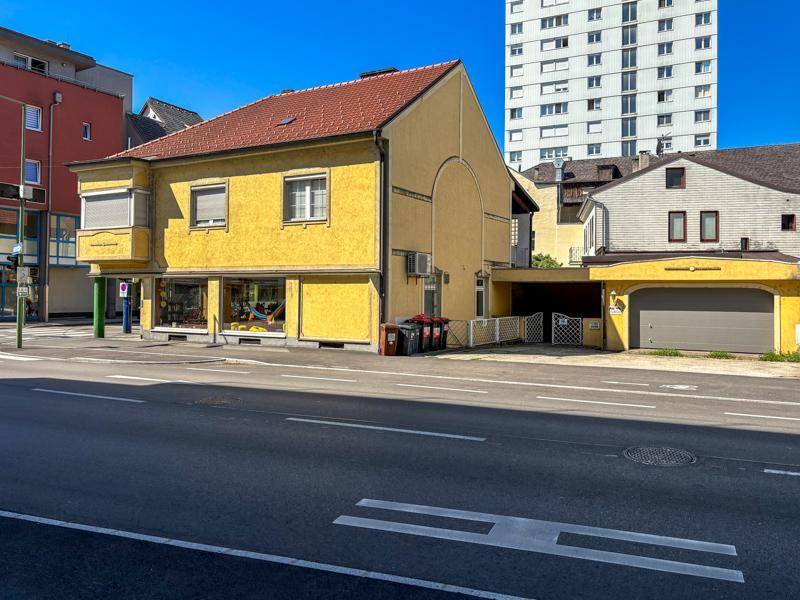 Seitenansicht des gelben Gebäudes mit Garagenzufahrt und Rampe, umgeben von städtischer Architektur.