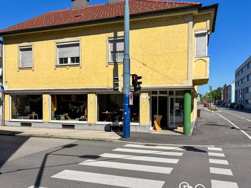 Detailansicht der gelben Fassade mit großen Schaufenstern im Erdgeschoss und Fußgängerüberweg.