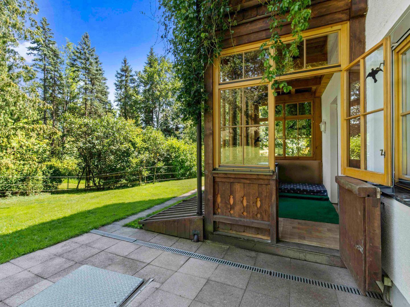 Hölzerner Erker mit Zugang zu einer kleinen Terrasse und Blick auf den weitläufigen Garten.