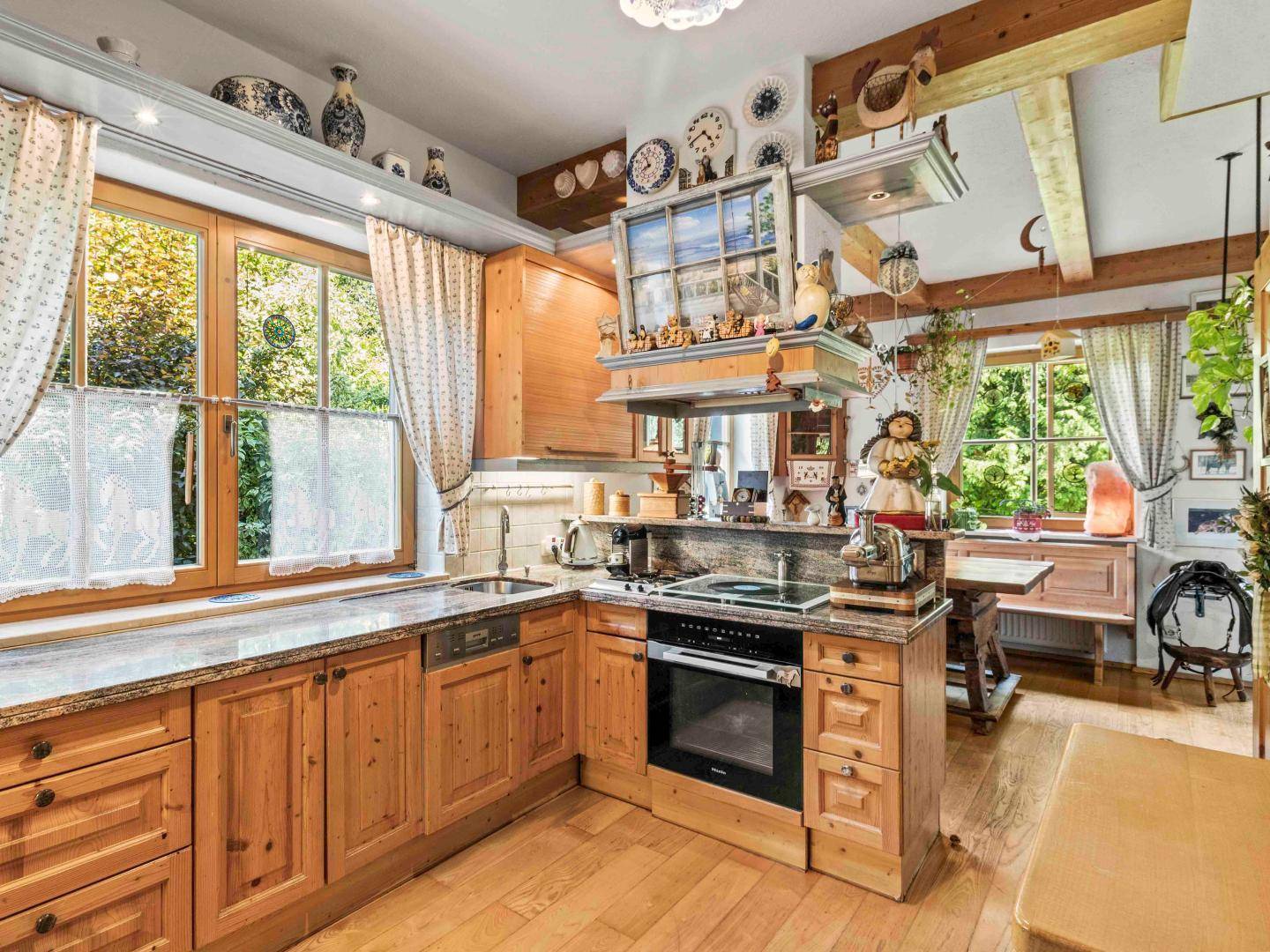 Traditionelle Holzküche mit Granitarbeitsplatten und modernen Geräten, hell durch große Fenster.