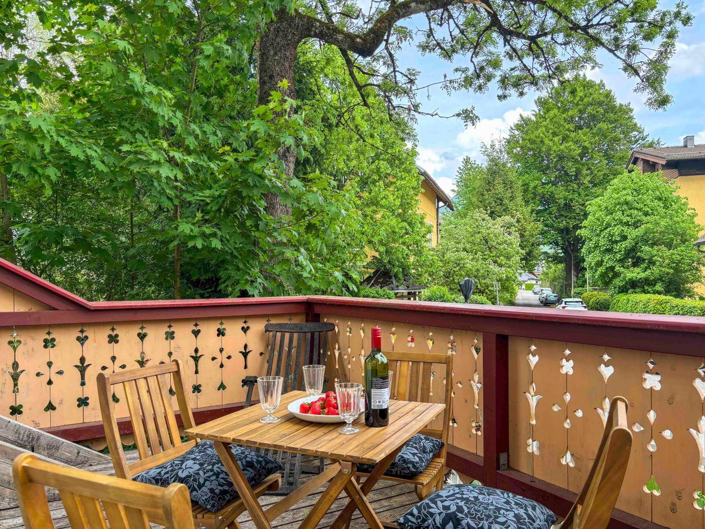 Gemütlicher Balkon mit Holztisch, Stühlen und Blick ins Grüne.