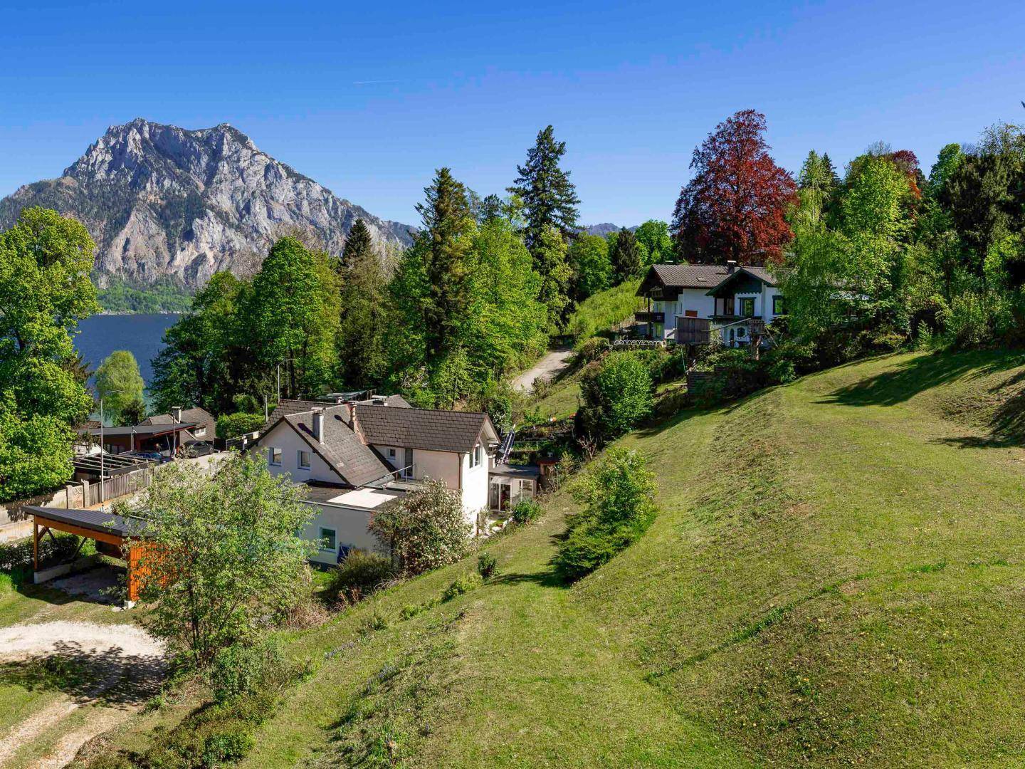 Luftaufnahme von zwei Häusern am Hang mit malerischem Blick auf den See und die Berge.