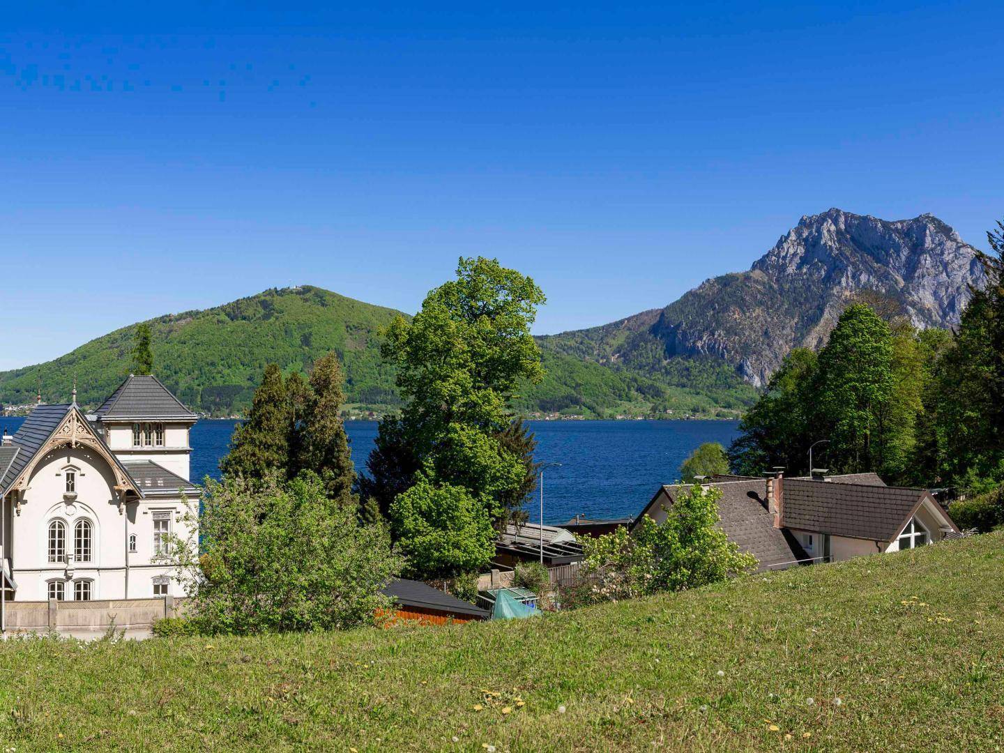 Idyllischer Ausblick auf den See und die majestätischen Berge, eingerahmt von zwei Häusern.