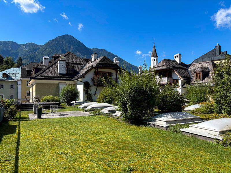 Gepflegter Gartenbereich mit Rasenfläche und Terrasse vor einer malerischen Bergkulisse.