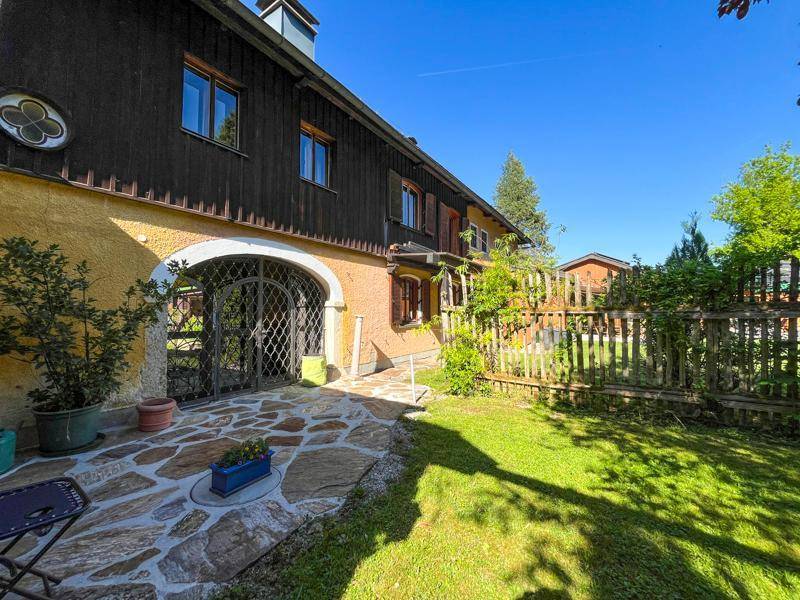 Seitlicher Gartenbereich mit Holzzaun, gepflastertem Weg und Zugang zum Gebäude.
