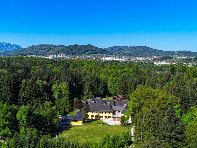 Luftaufnahme des Anwesens, umgeben von Wäldern und mit Blick auf die Stadt in der Ferne.
