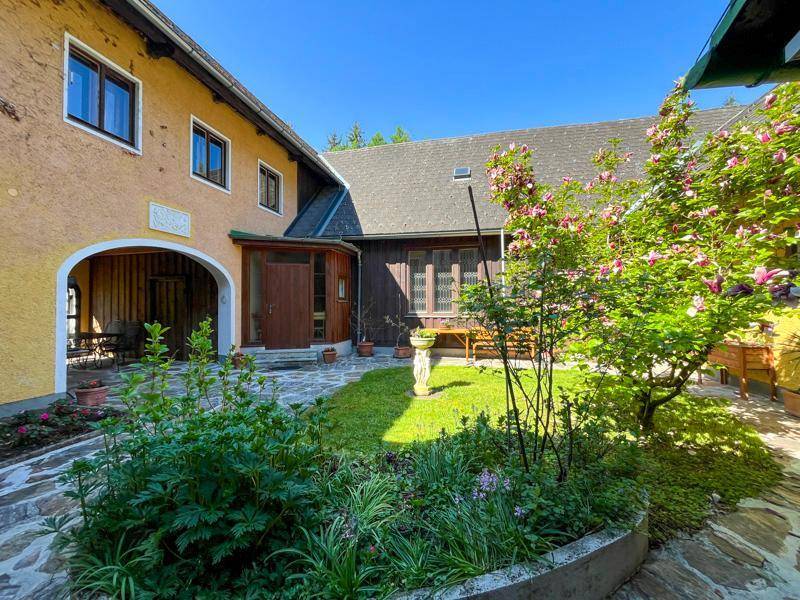Idyllischer Innenhof mit Blumenbeeten und gepflasterten Wegen zwischen den Gebäuden.