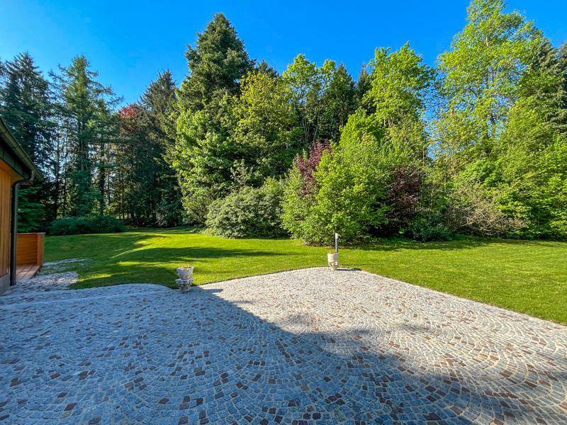 Gepflasterte Terrasse mit Blick auf den weitläufigen Garten und die umliegenden Bäume.