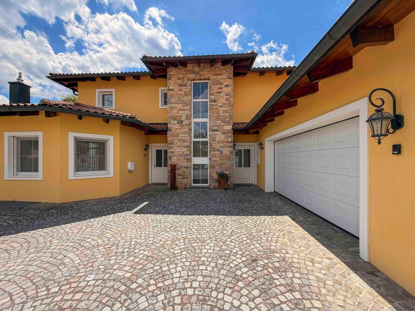 Eingangsbereich des Hauses mit Natursteinfassade und großer Doppelgarage.