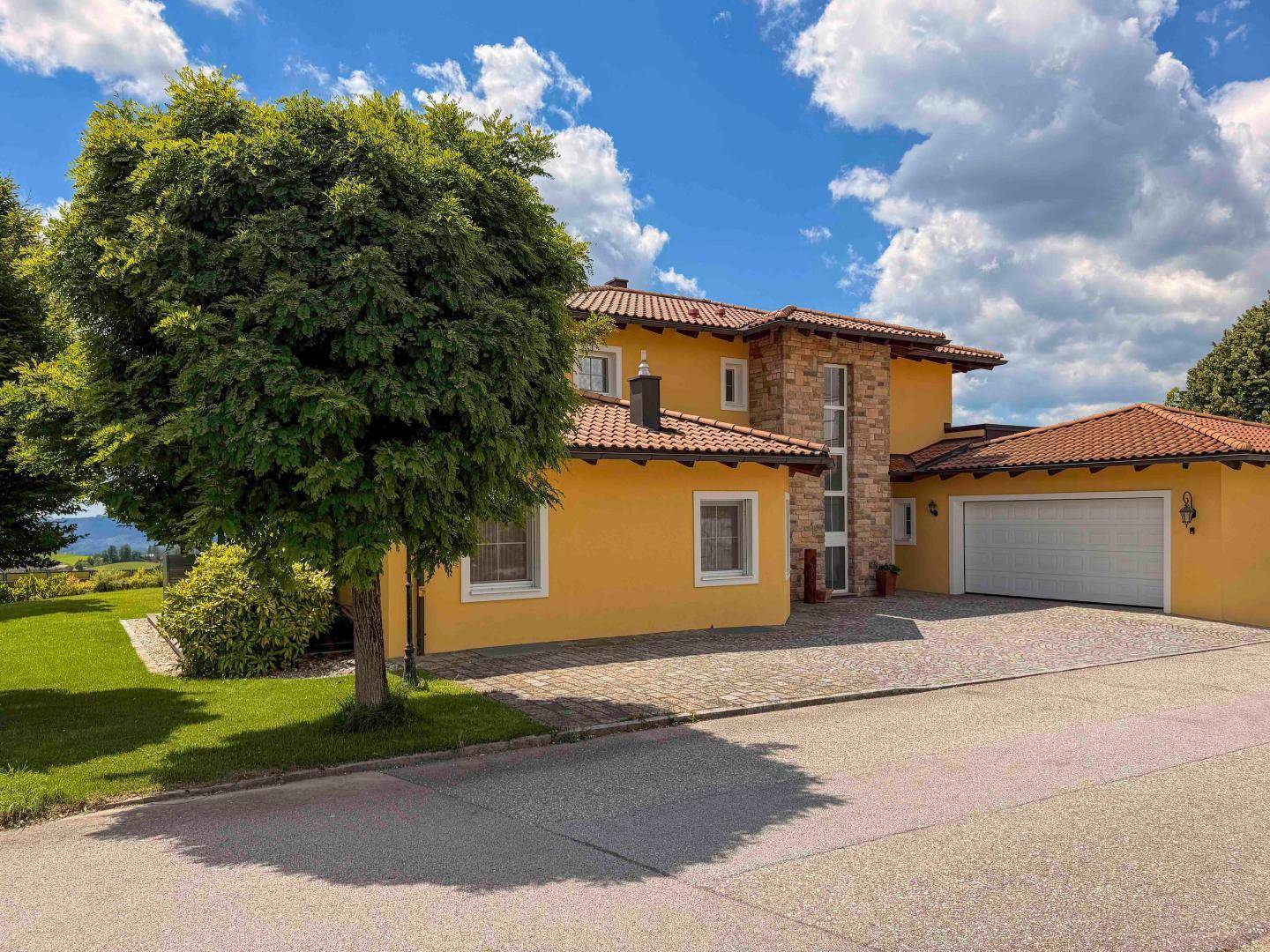 Ansicht des Hauses von der Straße mit gepflasterter Einfahrt und Garage.