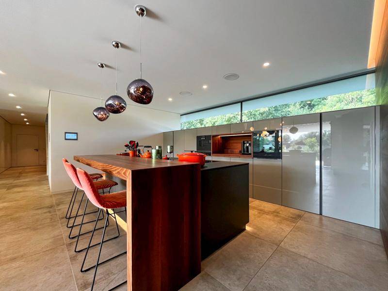 Moderne Küche mit Kochinsel, Frühstücksbar und integrierten Geräten in hellem Design.