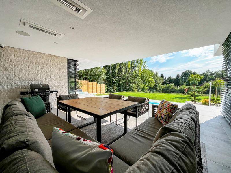 Überdachte Terrasse mit bequemen Loungemöbeln, Esstisch und Blick in den Garten.