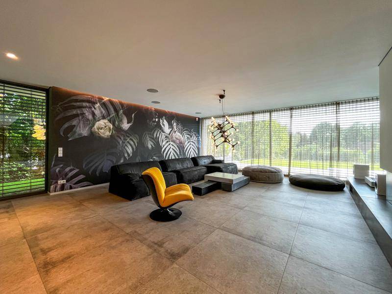 Großzügiges Wohnzimmer mit moderner Einrichtung, großer Couch und floraler Wandgestaltung.