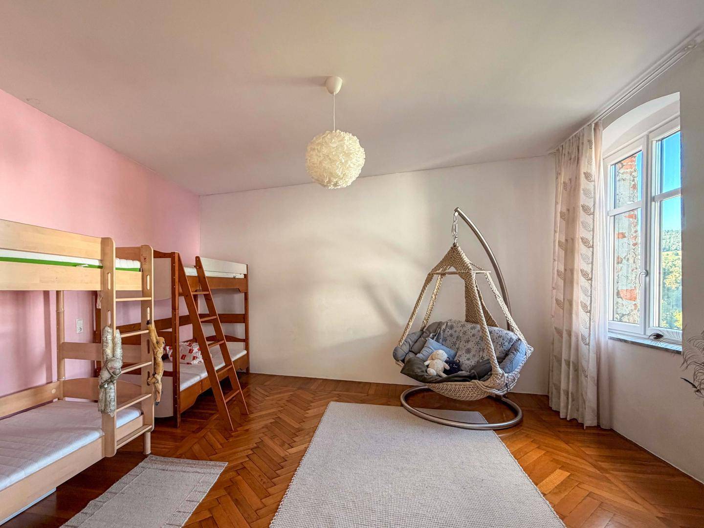Kinderzimmer mit Etagenbetten, Schaukelstuhl und Holzboden, hell und freundlich gestaltet.