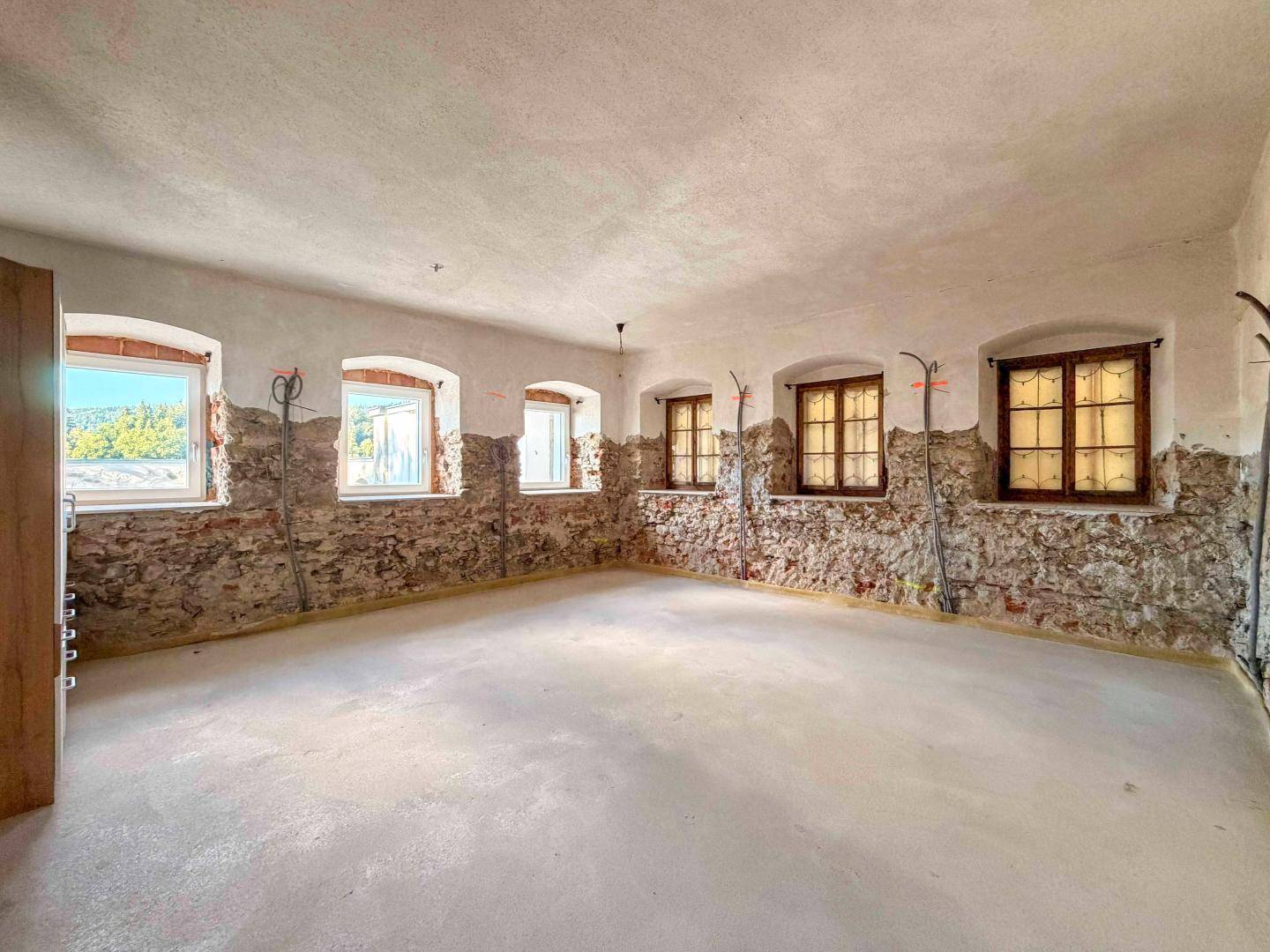 Rustikaler Kellerraum mit freigelegten Steinwänden und Betonboden, bereit für den Ausbau.