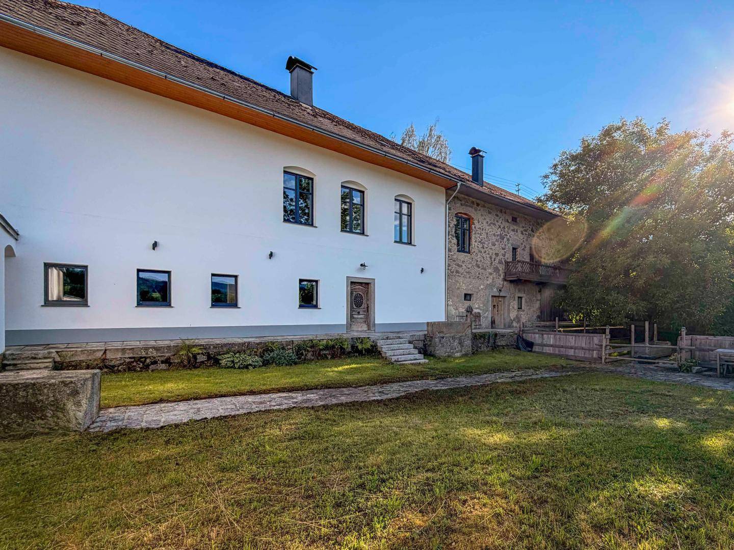 Weitläufiger Außenbereich mit gepflegtem Rasen und historischem Gebäude unter strahlendem Sonnenschein.