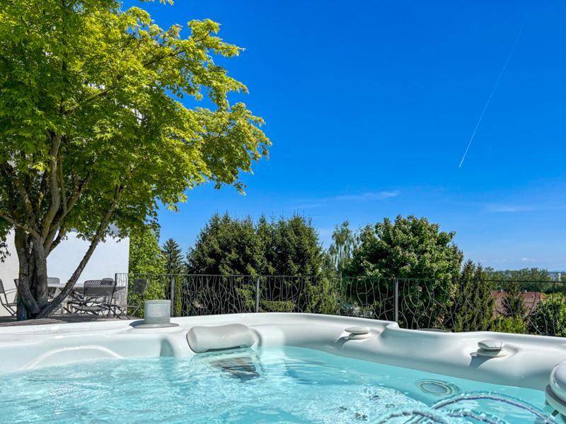 Entspannender Whirlpool im Freien mit Blick auf grüne Bäume und den weiten blauen Himmel.