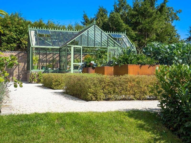 Detailansicht des Gewächshauses im Garten mit Hochbeeten für den Anbau von Gemüse.