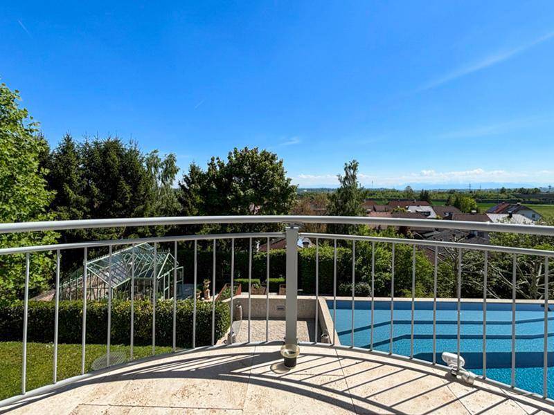 Runder Balkon mit Metallgeländer und weitem Blick auf den Pool und die grüne Umgebung.