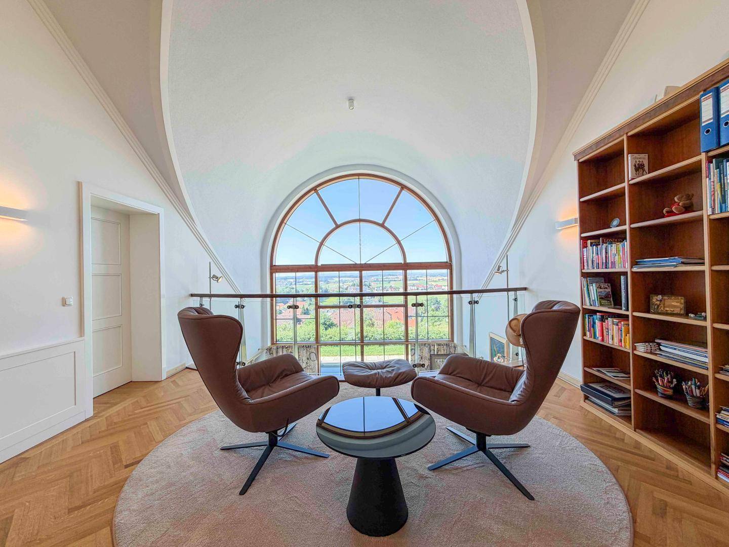 Gemütliche Leseecke auf der Galerie mit Bücherregal und großem Bogenfenster.