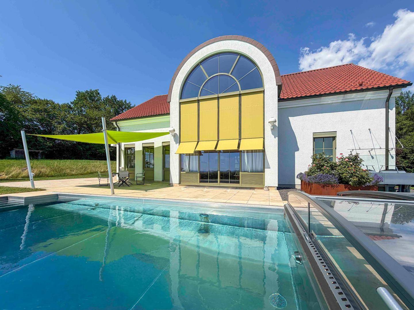 Moderner Poolbereich mit großer Fensterfront und Blick auf die weite Landschaft.