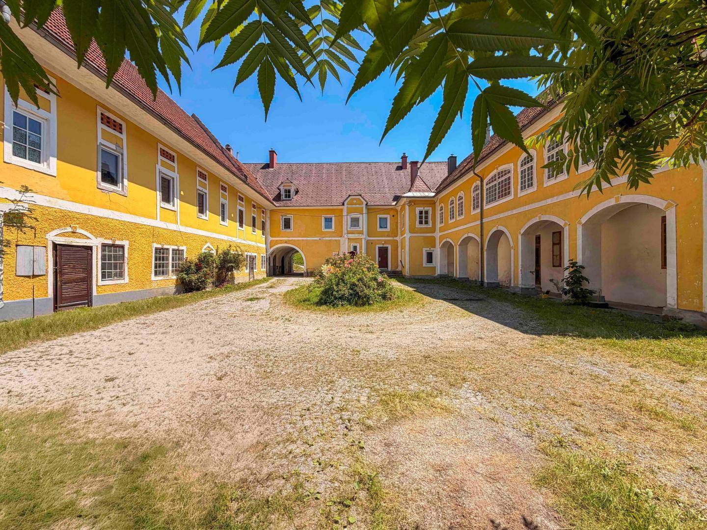 Innenhof des Anwesens mit gelben Fassaden und Arkaden, die eine historische Atmosphäre schaffen.