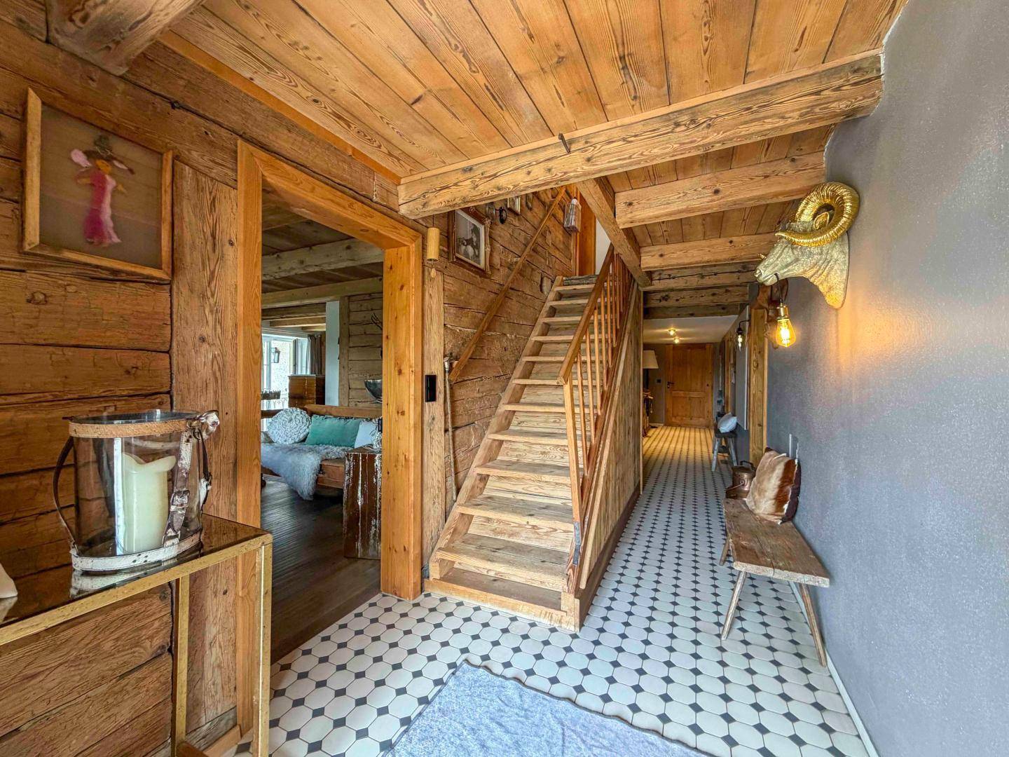 Rustikaler Eingangsbereich mit Holzbalken, gemusterten Fliesen und Treppe zum Obergeschoss.