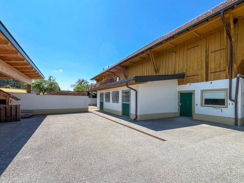 Geräumiger Außenbereich mit Kiesfläche und Zugang zu den Stallungen und Nebengebäuden.