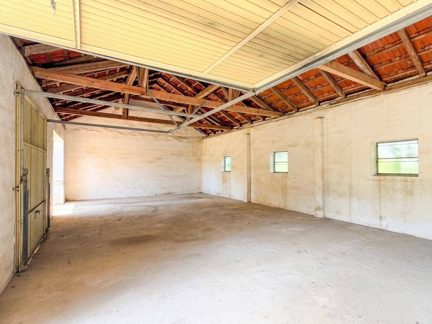 Geräumige Garage mit Betonboden, hohen Decken und sichtbarer Dachkonstruktion.