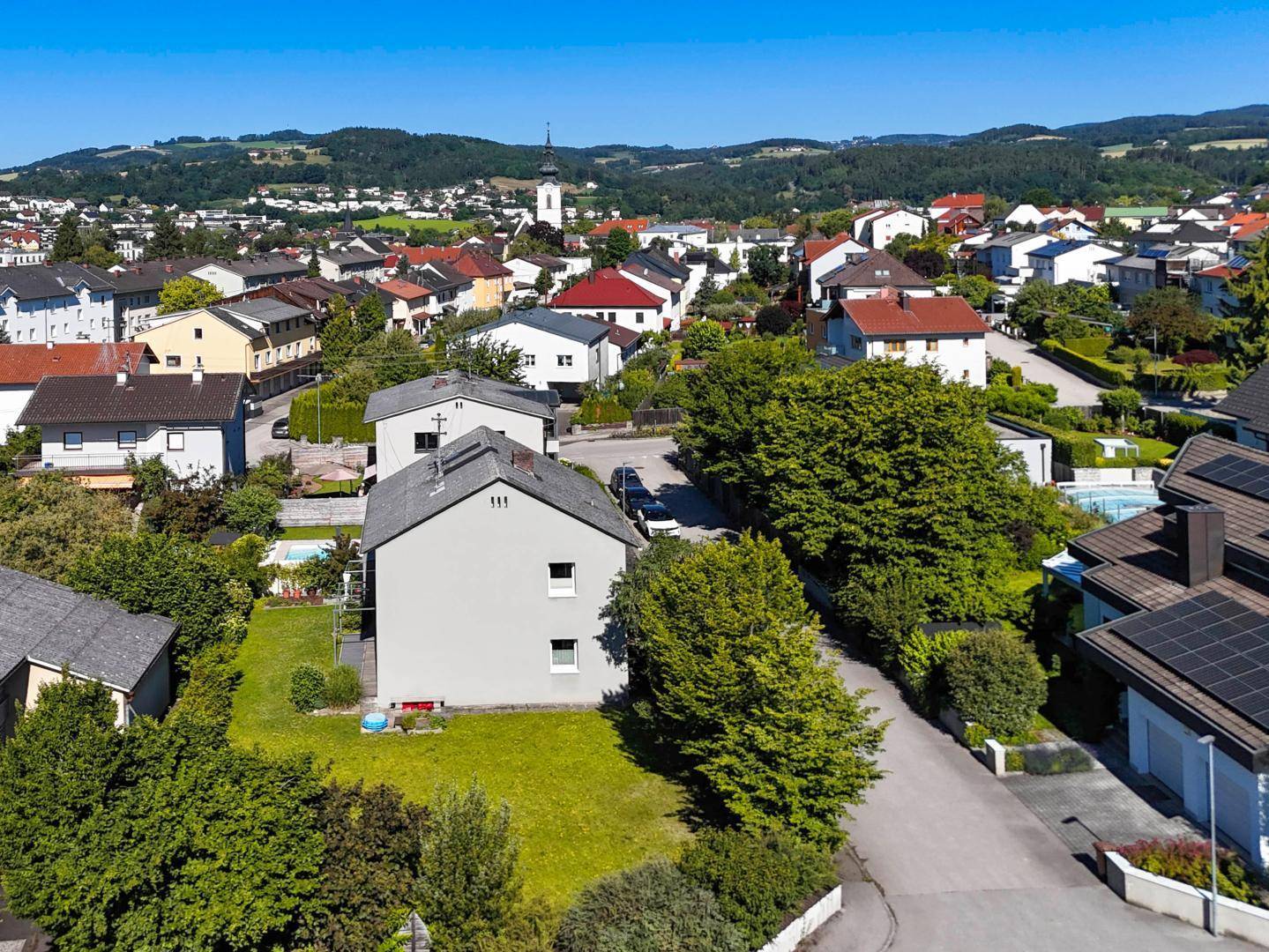 Luftaufnahme des Hauses in einer Wohnsiedlung mit umliegender grüner Landschaft.