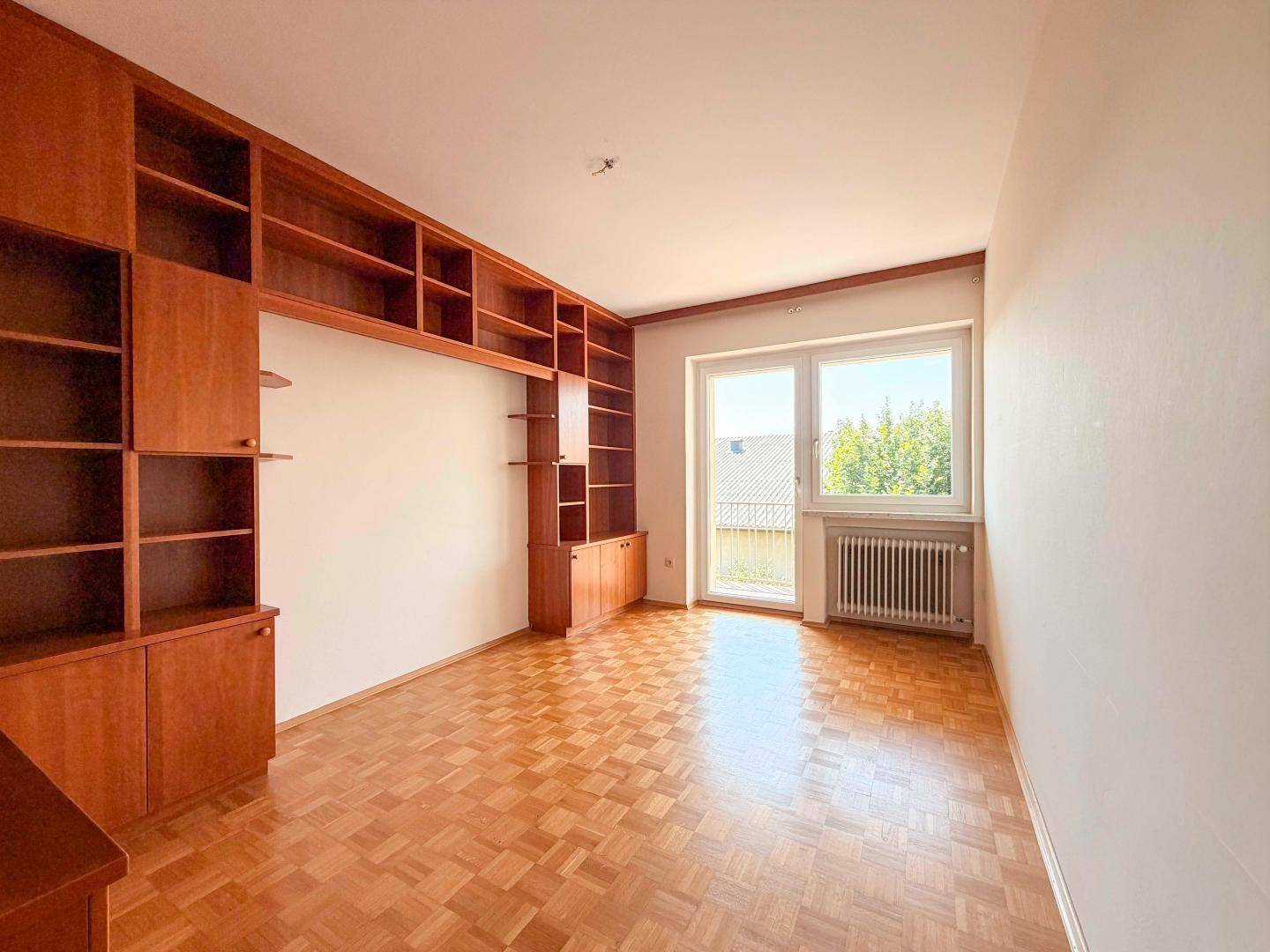 Zimmer mit Parkettboden und großer Holzregalwand, ideal als Büro oder Arbeitszimmer.