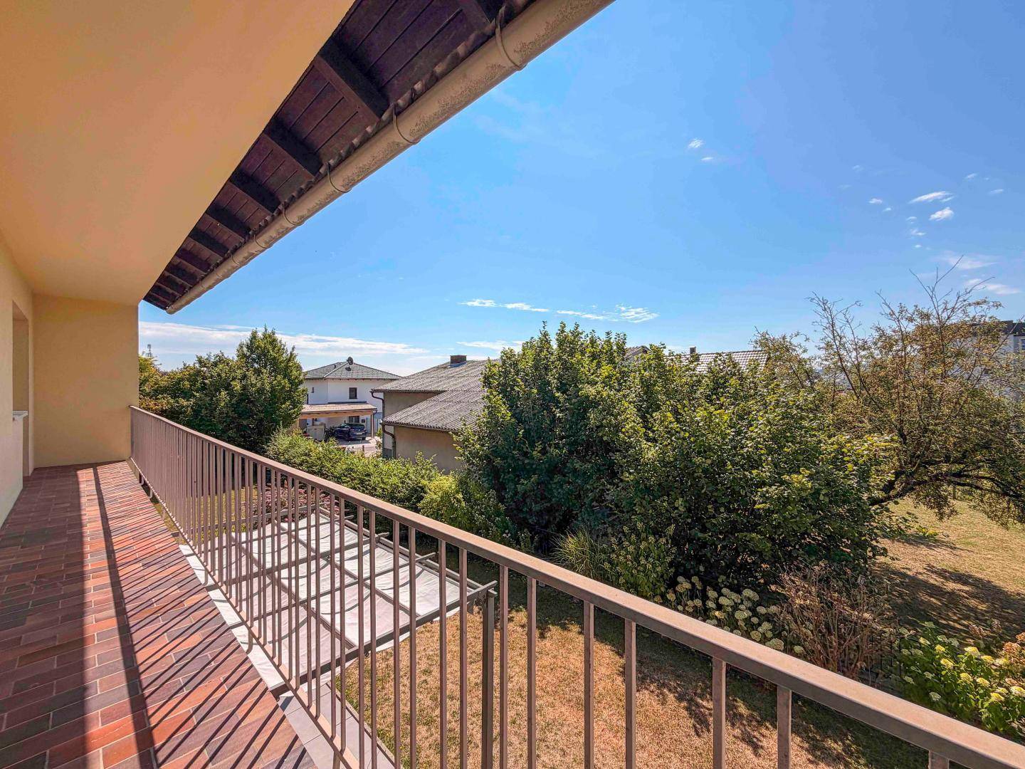 Blick vom Balkon auf die umliegenden Häuser und den grünen Gartenbereich.