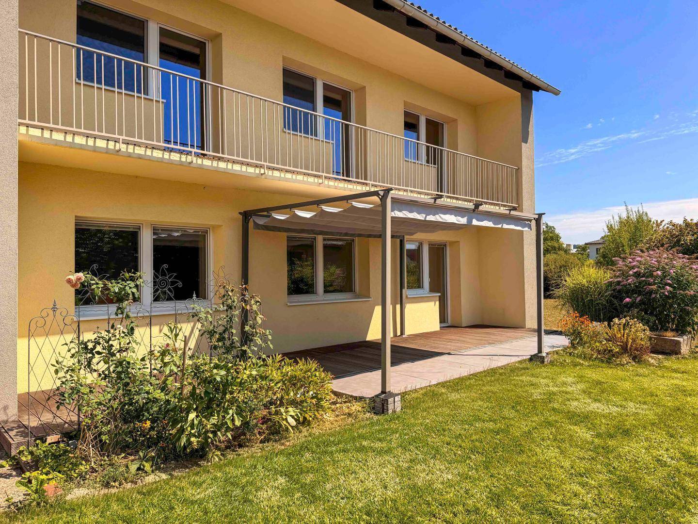 Nahaufnahme der Holzterrasse mit Pergola und Zugang zum Gartenbereich des Hauses.